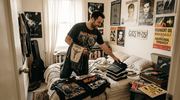 Collector sorting vintage band shirts in bedroom