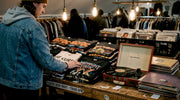 Person sorting vintage band shirts in thrift shop