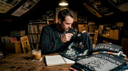 Collector examines vintage band t-shirts at home