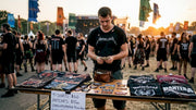 Merch seller arranging metal band t-shirts