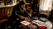 Person reviewing vintage heavy metal tour shirts collection