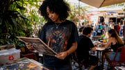 Young woman browsing vintage band t-shirts outdoors