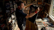 Collector examining vintage bootleg shirt indoors
