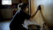 Person cleaning nicotine stain from wall